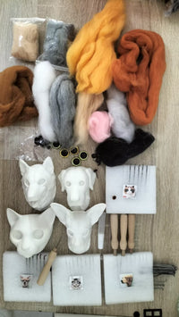 Needle felting kit contents laid out: colored wool rovings, foam cat and dog head forms